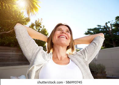 Portrait of happy older woman smiling with hands behind head
