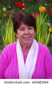 Portrait Of Happy Older Woman Smiling In Garden With Tulips Background