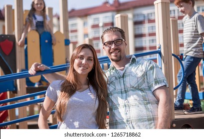 Porträt glücklicher Eltern auf dem Spielplatz.