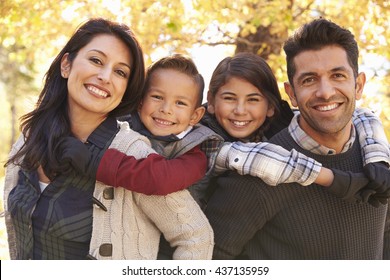 Portrait of happy parents piggybacking kids outdoors