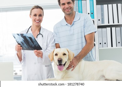 Portrait Of Happy Pet Owner And Veterinarian With Xray Of Dog In Hospital