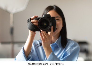 Portrait Of Happy Photographer Lady Taking Photo Holding Camera Near Face And Smiling Standing In Modern Studio Indoors. Professional Photography Art And Career, Creative Professions Concept