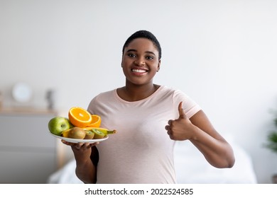 Portrait Of Happy Plus Size Black Woman Holding Plate Of Fruits And Showing Thumb Up Gesture, Recommending Healthy Diet For Weight Loss At Home. Body Care, Slimming, Good Nutrition Concept