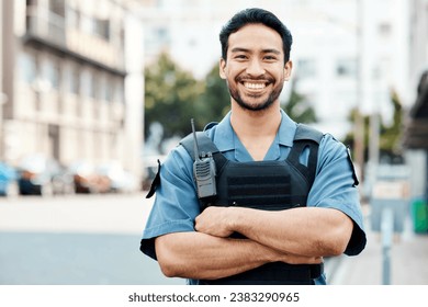 Portrait, happy or policeman in city with arms crossed for law enforcement, surveillance or street safety. Confident cop, smile or proud Asian security guard on patrol in town for crime or justice