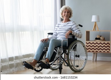 Portrait Of Happy Positive Handicapped Old Woman Sitting In Wheelchair Feel Optimistic At Home Or Retirement House, Smiling Senior Disabled Female In Invalid Carriage Wheel Chair Look At Camera