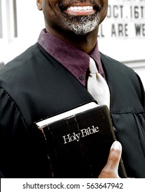 Portrait of happy preacher holding Holy Bible while standing in front of church