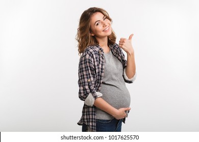 portrait of happy pregnant woman showing thumb up isolated on grey