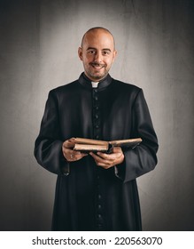 Portrait Of  A Happy Priest That Reads A Bible