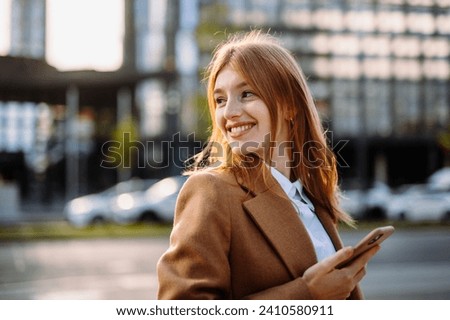 Portrait of a Happy Professional in Formal Attire, Flashing a Smile and Gesturing, with Layered Hair and Eyewear, Sitting on a City Street, Holding a Mobile Phone