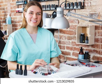 Portrait of happy professional nail master sitting at working place  to salon - Powered by Shutterstock