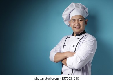 Portrait Of Happy Proud Asian Chef Smiling At Camera With Crossed Arms, Against Blue Background