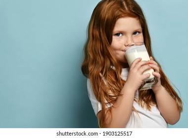 Portrait Of Happy Red Haired Kid Girl Drinking Milk Or Yogurt And Looking At Camera Over Blue Background With Free Copy Space. Health And Diet Concept. Healthy Drink Breakfast And Clean Food Concept