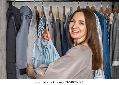 Portrait Happy Redhead Woman Choosing Clothes At Modern Comfortable Storage Organized Capsule Wardrobe Apparel Assortment. Smiling Female Posing Hanged Fashion Apparel At Home Cupboard Ready To Event