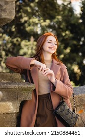 Portrait Of Happy Redhead Woman In Coat Looking Away Outside