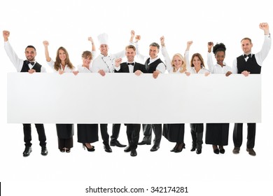 Portrait Of Happy Restaurant Staff With Arms Raised Holding Blank Billboard Against White Background