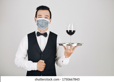 Portrait Of Happy Restaurant Waiter In Medical Mask Serving Glass Of Red Wine