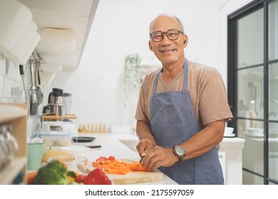 Portrait Of Happy Retired Asian Senior Man Standing While Cooking In Kitchen