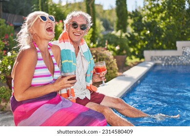 Portrait happy, retired, carefree senior couple laughing and drinking cocktails at sunny summer swimming pool, enjoying vacation getaway - Powered by Shutterstock