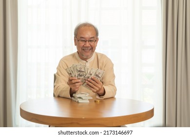 Portrait Of Happy Rich Asian Thai Old Senior Retired Man Counting Money To Save Banknote In Financial Account And Investment Concept On Table At Home Or House. People Lifestyle. Win Lottery