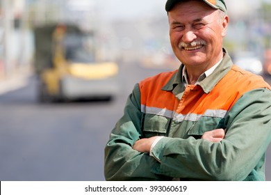 Portrait Happy Road Worker On Asphalt Roller Machine Background During Construction Resurfacing For Driveways Or Tarmac Repairing Works