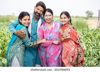 Portrait of Happy rural indian parents with their young beautiful daughters standing outdoor in agriculture field. cheerful husband and wife smiling with children.  wearing traditional outfit.  - Shutterstock ID 2015984093