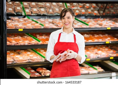 Portrait of happy saleswoman holding meat packages at counter in butcher's shop - Powered by Shutterstock