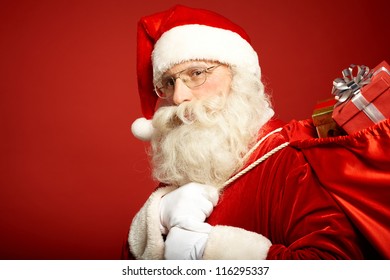 Portrait of happy Santa Claus with big red sack looking at camera