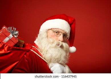 Portrait of happy Santa Claus with big red sack looking at camera