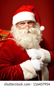 Portrait of happy Santa Claus holding sack with gifts and looking at camera