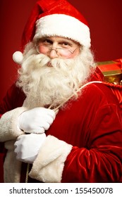 Portrait of happy Santa Claus holding sack with gifts and looking at camera