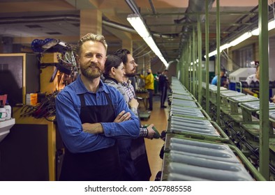 Portrait of happy satisfied bearded male worker standing in shoe manufacturing workshop at footwear making factory. Concept of mass leather footwear production industry