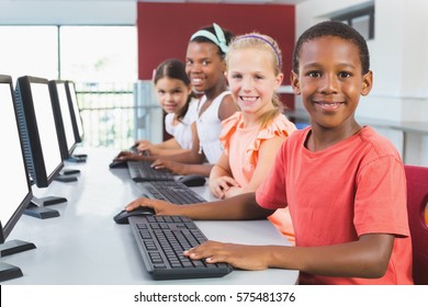 Portrait Of Happy School Kids Using Computer In Classroom At School