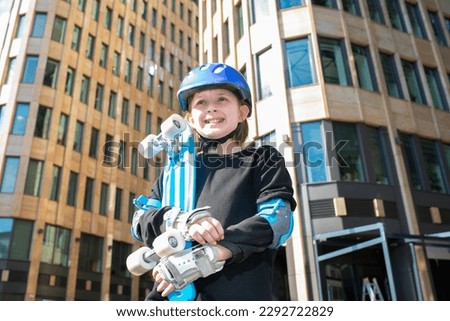 portrait of happy schoolboy in purple helmet, holding blue urban cruiser, skateboard.