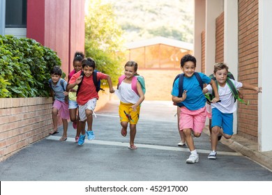 Portrait Of Happy Schoolchildren Running On Footpath