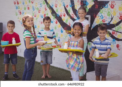 Portrait of happy schoolkids holding meal in tray at school - Powered by Shutterstock