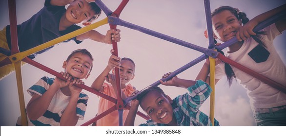 Portrait of happy schoolkids looking through dome climber at school playground - Powered by Shutterstock