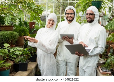 Portrait of happy scientists in clean suit using technologies at greenhouse - Powered by Shutterstock