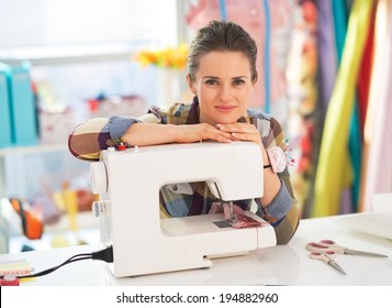Portrait of happy seamstress with sewing machine