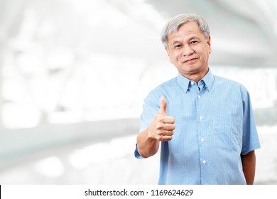 Portrait of happy senior asian man gesture hand showing thumb up or good sign and looking at camera on isolated background feeling positive and satisfaction. Older mature male lifestyle concept.