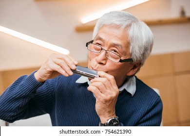 Portrait Of Happy Senior Asian Man Playing Harmonica