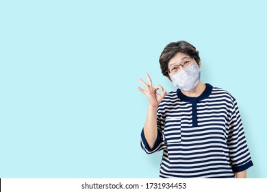 Portrait Of Happy Senior Asian Woman Wear Face Mask And Gesture Or Showing Hand Ok And Looking At Camera On Isolated Background Feeling Positive Enjoy And Satisfaction. Older Female Protection Virus