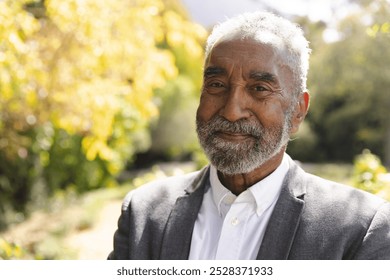 Portrait of happy senior biracial man smiling in sunny garden at home, copy space. Happiness, nature, wellbeing, summer and senior lifestyle, unaltered. - Powered by Shutterstock