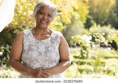 Portrait of happy senior biracial woman smiling in sunny garden at home, copy space. Happiness, nature, wellbeing, summer and senior lifestyle, unaltered. - Powered by Shutterstock