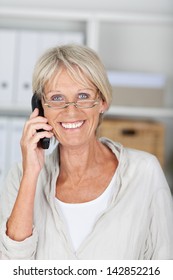 Portrait Of Happy Senior Businesswoman Conversing On Cordless Phone At Office