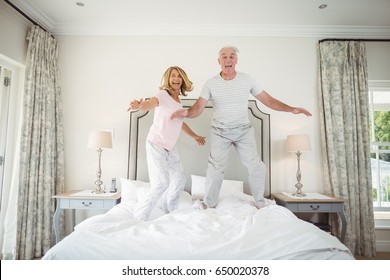 Portrait of happy senior couple dancing on bed in bedroom - Powered by Shutterstock