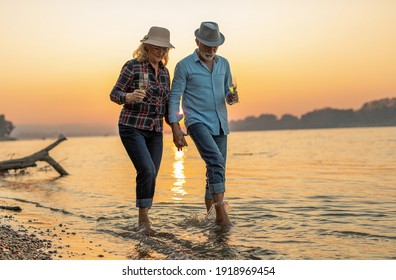 Portrait of a happy senior couple drinking wine and enjoying the sunset on the river.	 - Powered by Shutterstock