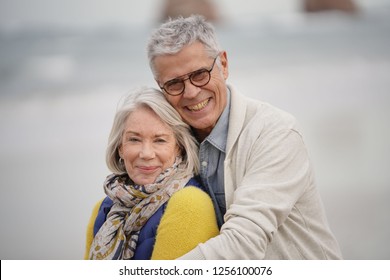  Portrait of happy senior couple embracing on the beach                              