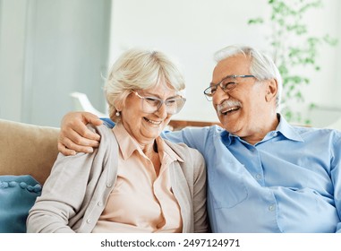 Portrait of a happy senior couple embracing talking and drinking coffee or tea at home - Powered by Shutterstock