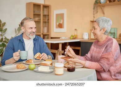 Portrait of happy senior couple enjoying breakfast together in cozy kitchen and smiling looking at each other - Powered by Shutterstock