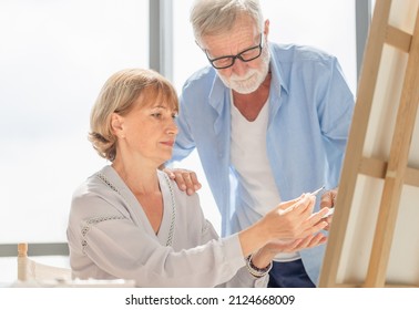 Portrait Of Happy Senior Couple Painting On A Canvas In Living Room, Older Man And Woman Drawing Together On A Canvas, Happy Retirement Concepts